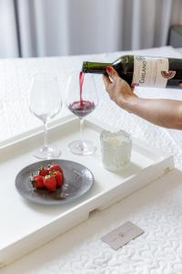 a person pouring a bottle of wine and a plate of strawberries at Feel Home - Flat Romântico com Piscina no Rooftop in Cabedelo