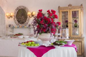 a table with a vase filled with red flowers and fruit at Lukka Exclusive Hotel – Adult Only +12 in Kaş