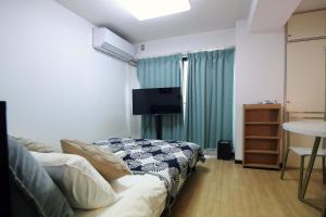 a room with a bed and a tv and a table at Nogata House in Tokyo