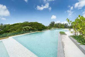 a swimming pool with blue water and trees in the background at Laguna Beachside Residents in Phuket