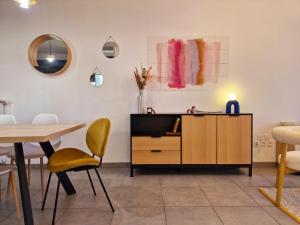 a living room with a tv and a table and chairs at Luminea - Apt T3 avec parking souterrain - Aéroport Blagnac, MEET et tram in Blagnac