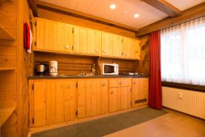 eine Küche mit Holzschränken, einem Waschbecken und einem Fenster in der Unterkunft MOM - Alpine Boutique Apartments, Romantica, near Grindelwald Terminal in Grindelwald