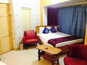 a bedroom with a bed and a chair and a table at Hotel Bengal in Kolkata