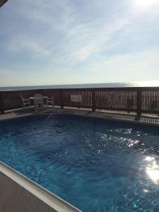 a swimming pool with two chairs and a wooden fence at Windswept Motel in Point Pleasant Beach