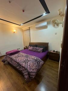 a bedroom with a bed with a purple comforter at Gulberg Heights in Islamabad