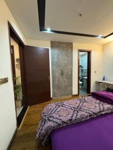 a bedroom with a bed with a purple comforter at Gulberg Heights in Islamabad