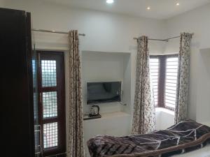 a bedroom with a bed and a tv and windows at Pushkarni Home Stay in Varanasi