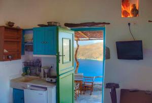 a kitchen with a green door and a table and a television at Pano Gitonia in Aegiali