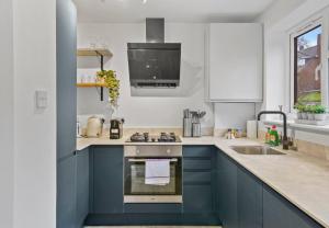 eine Küche mit blauen Schränken und einer Spüle in der Unterkunft Aisiki Apartments at Barnet, Ground Floor, 2-Bedroom & 1-Bathroom, Pet Friendly Flat, Double Beds with Free Wi-Fi in Barnet