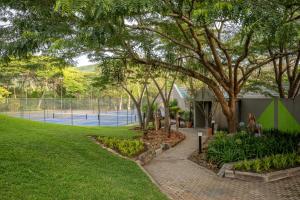 a park with a tree and a tennis court at First Group Sanbonani Resort in Hazyview +215 photos
