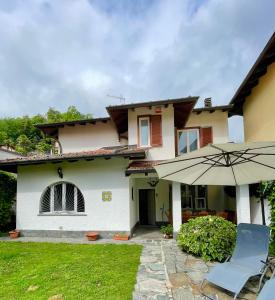 a house with an umbrella and a chair and a lawn at Villa Mia Lugano Lake in Brusimpiano