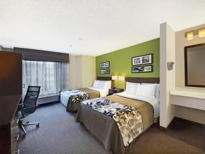 a hotel room with two beds and a flat screen tv at Baymont by Wyndham Fort Collins in Fort Collins