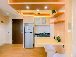 une cuisine avec un réfrigérateur blanc et une table dans l'établissement Good Place and Spacious Studio Transpark Cibubur Apartment By Travelio, à Depok