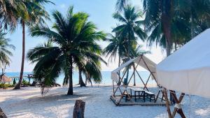 a tent and chairs on a beach with palm trees at Sunshine Resort Hotel Coconut Beach Koh Rong in Phumĭ Kaôh Rŏng