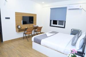 a hotel room with a bed and a desk and a tv at Hotel Vista Airport Zone in Shamshabad
