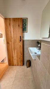 a bathroom with a sink and a wooden door at Plum Cottage Somerset in Wells +29 photos