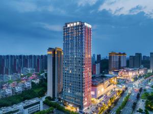 een hoog gebouw in een stad 's nachts bij Li Yi Hotel Yichang Zhongnan Road Changjiang Plaza Branch in Yichang