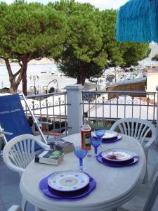a table with plates and wine glasses on a balcony at Marina Azzurra VistaMare - HiTuscany in Marina di Campo