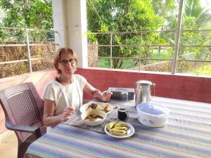 a woman sitting at a table with a plate of food at Kannur west beach house in Kannur