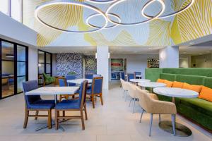 a restaurant with tables and chairs and a green couch at Hampton Inn Jacksonville - I-95 Central in Jacksonville