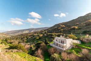 a white house in the middle of a mountain at Moraki Apartment 2 Andros in Korthi