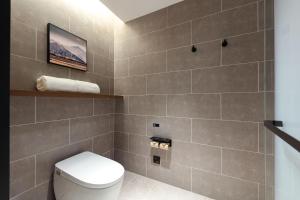 a bathroom with a toilet and a tiled wall at Atour Hotel Changsha Headquarters University of Science and Technology in Changsha