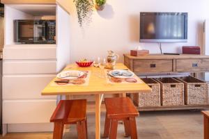 una cucina con tavolo in legno, sedie e TV di Le Bleuet - Vue montagne pistes accessibles à pied a Chamrousse