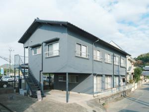 熊本Kotobukisou 民泊ことぶき荘 Free Parking 10 mins by car Kumamoto Station的灰色的建筑,设有窗户和楼梯