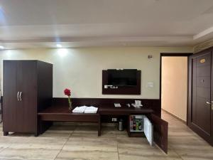 a living room with a desk and a tv on the wall at Hotel Anant Restaurant And Bar in Mandi