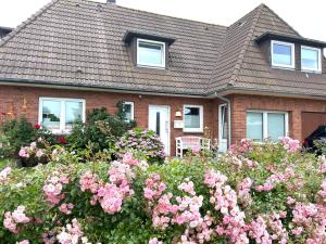 韦斯特兰Wohnung-Moewe-2的前面有粉红色花的房子