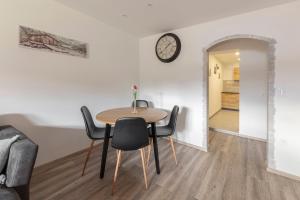 a table and chairs in a room with a clock on the wall at Apartmaji Hodak in Bohinj
