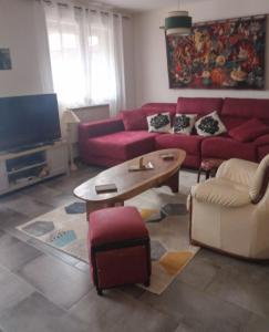ein Wohnzimmer mit einem roten Sofa und einem Couchtisch in der Unterkunft Maison entre mer et montagne in Pollestres