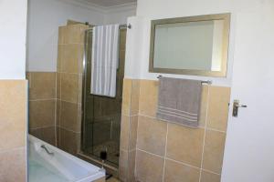a bathroom with a shower with a tub and a mirror at Glen Rest Country Lodge in Midrand