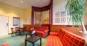 une salle d'attente avec des canapés rouges et une table dans l'établissement PLAZA INN Chemnitz, à Chemnitz