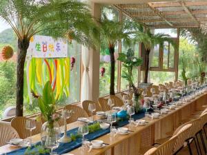 桂林市にあるGuilin Red Roof Garden Resort --Within 8000 square meter lush garden- Fluent English-Southeast Asian style decoration-Quiet and delightfulのヤシの木の間の長テーブル