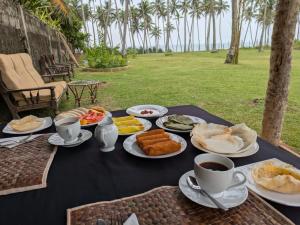 a table with plates of food and cups of coffee at Coconut Tree hill Rekawa in Tangalle