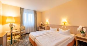 a hotel room with a white bed and a desk at PLAZA INN Chemnitz in Chemnitz +59 photos