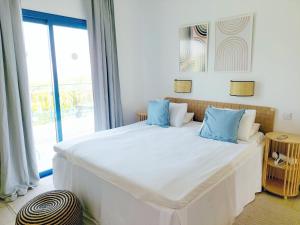 a bedroom with a large white bed with blue pillows at Azzurro Holiday Villas in Peyia