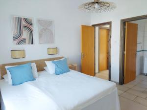 a bedroom with a large white bed with blue pillows at Azzurro Holiday Villas in Peyia