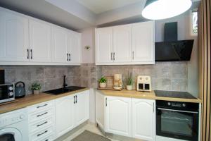 a kitchen with white cabinets and a stove top oven at The Greens premium house - Luxury Apartment in the Heart of the City by Villa Mana Gers in Zakynthos Town