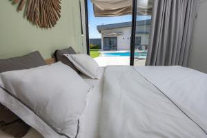 a bed with white sheets and pillows in a bedroom at נופש Eylim-מתחם אירוח מהמם עם 3 סוויטות ובריכה מחוממת ומקורה in Sede Ẕevi