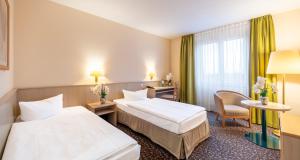 a hotel room with two beds and a chair at PLAZA INN Chemnitz in Chemnitz