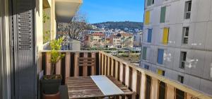 einen Balkon mit einer Holzbank und Stadtblick in der Unterkunft Appartement moderne à Nice, 50 m² avec balcon in Nizza