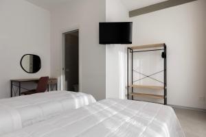 a white bedroom with a white bed and a mirror at Associazione Garage24 Aps Ets in Portoferraio