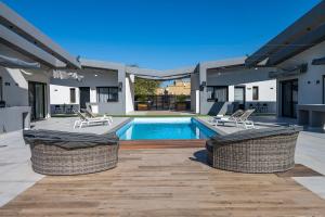 a house with a swimming pool and two chairs at נופש Eylim-מתחם אירוח מהמם עם 3 סוויטות ובריכה מחוממת ומקורה in Sede Ẕevi