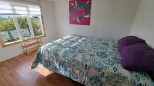 a bedroom with a bed with a comforter and a window at Cabaña Ecológica El Puesto in Puerto Natales