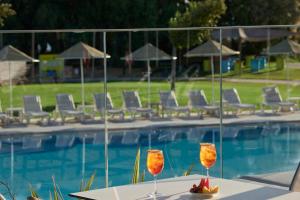 two wine glasses sitting on a table next to a pool at TUI Magic Life Candia Maris - Adults Only in Amoudara Herakliou