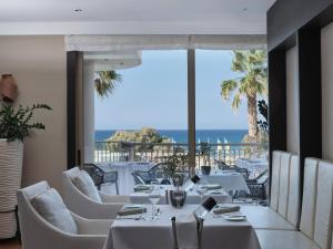 a restaurant with white tables and chairs and the ocean at TUI Magic Life Candia Maris - Adults Only in Amoudara Herakliou
