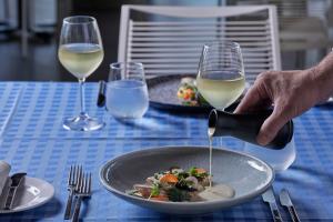 a person is pouring white wine into a bowl of food at TUI Magic Life Candia Maris - Adults Only in Amoudara Herakliou