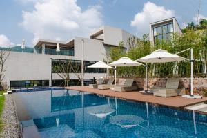a swimming pool with chairs and umbrellas in front of a building at Nian hotel & resorts in Huzhou